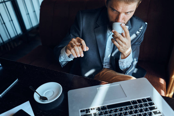 Biznes człowiek siedzi w kawiarni przed laptopem z filiżanką kawy technologii stylu życia - Zdjęcie, obraz