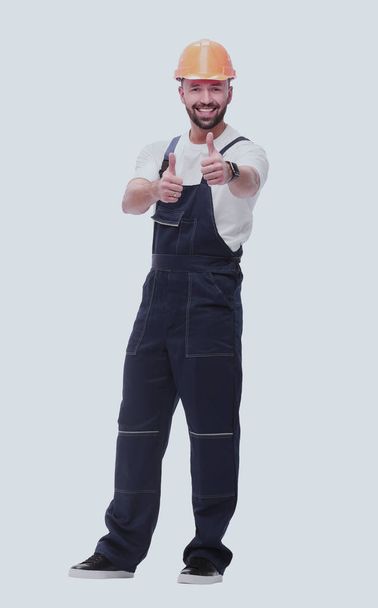 smiling man in overalls showing thumbs up . isolated on white - Zdjęcie, obraz