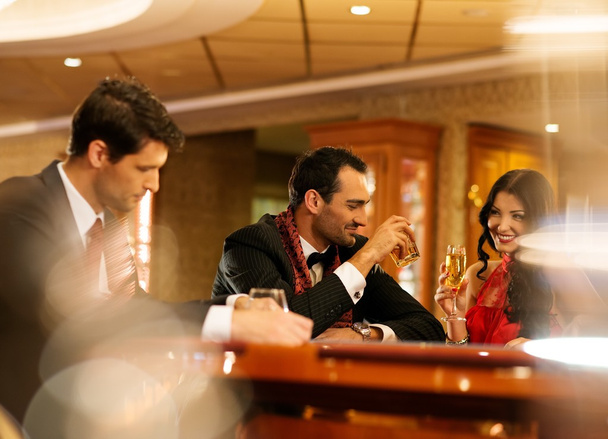 Happy young people behind gambling table with drinks - Foto, Bild