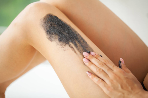 Hautpflege, Frau trägt schwarzes Peeling mit Meersalz auf - Foto, Bild