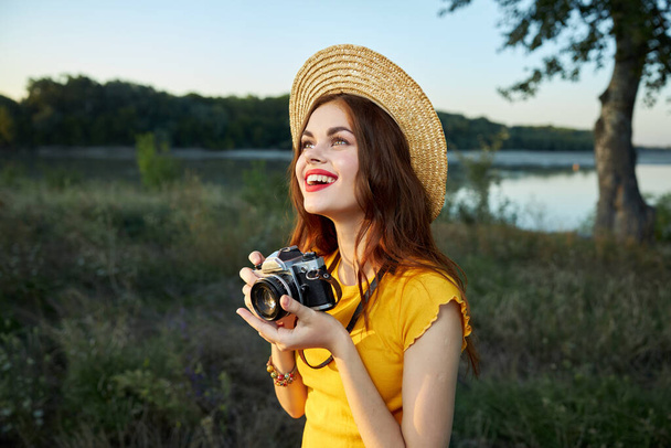Kobieta w przyrodzie fotograf aparat w rękach uśmiech spojrzeć w górę kapelusz - Zdjęcie, obraz