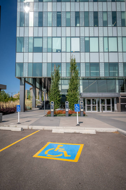 Wheel chair sign freshly painted in parking spot of modern building. - Photo, Image