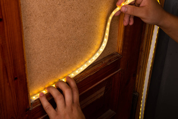 montaż listwy LED z ciepłym żółtym światłem na drzwiach do oświetlenia dekoracyjnego - Zdjęcie, obraz