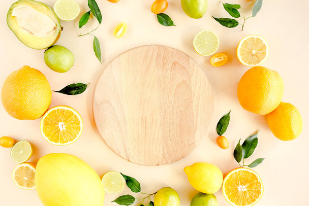 Board frame and summer tropical fruits: orange, lemon, lime, mango on yellow background. Food concept. flat lay, top view - Zdjęcie, obraz