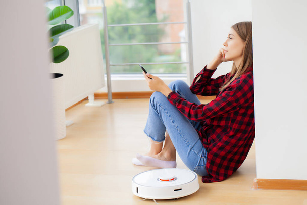 Woman turns on smart robot vacuum cleaner - Photo, Image