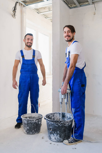 Twee reparateurs kneden cement met een bouwmixer - Foto, afbeelding