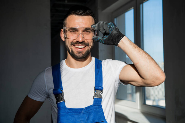 Foreman v modrých montérkách a brýlích s úsměvem - Fotografie, Obrázek
