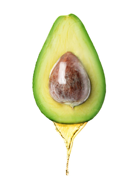 Avocado oil dripping from fresh fruit on white background - Фото, изображение