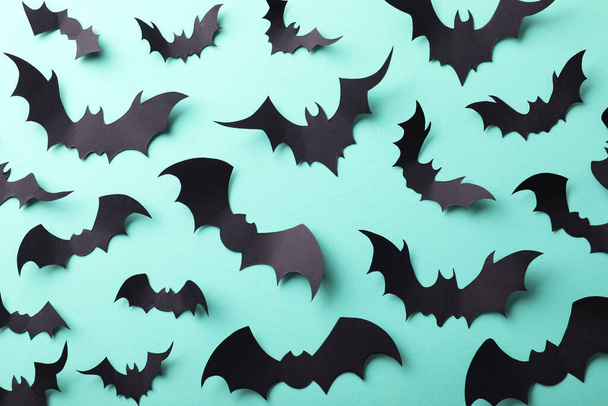 Many black paper bats on light blue background, flat lay. Halloween decor - Foto, Imagen