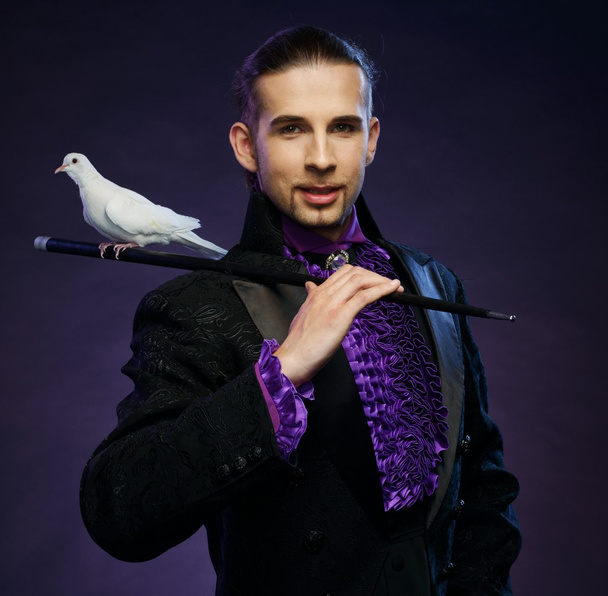 jonge knappe brunette tovenaar man in fase kostuum met zijn opgeleide witte duiven - Foto, afbeelding