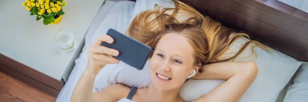 Relaxed woman using a smart phone on the bed at home BANNER, LONG FORMAT - Fotó, kép