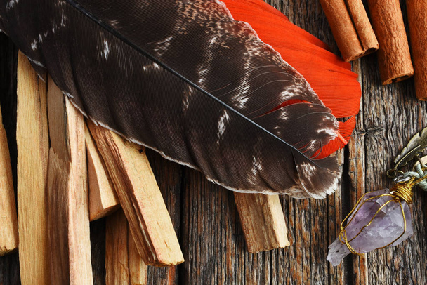 Une image de vue du dessus d'une plume sacrée marron et pendule améthyste maison sur une table en bois.  - Photo, image