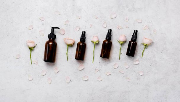 Delicate skin care cosmetic feminine flatlay. Top view Creative composition of face cream ,glass bottles and jars with cosmetic and flowers leaves on abstract background - Photo, Image
