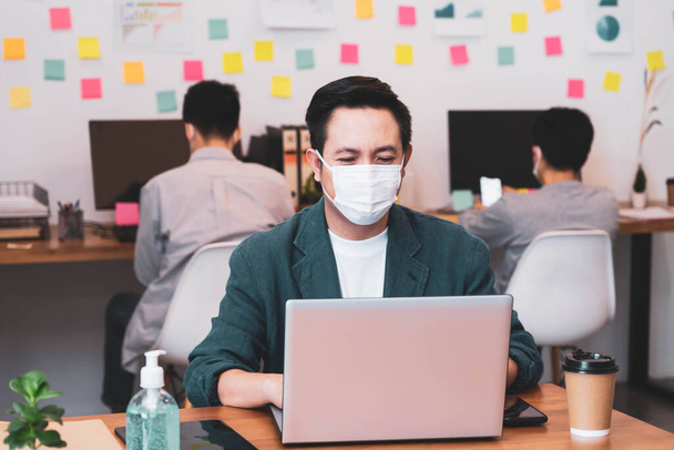 Young asian businessman wearing protective mask for covid19 protection corona flu prevent healty ideas concept office background.The work with new normal lifestyle in office. - Foto, afbeelding
