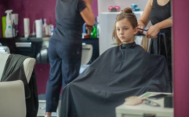 Гарна молода європейська дівчина сидить у салоні краси, професійному перукарському стилістському стилі з довгим волоссям дівчини.. - Фото, зображення