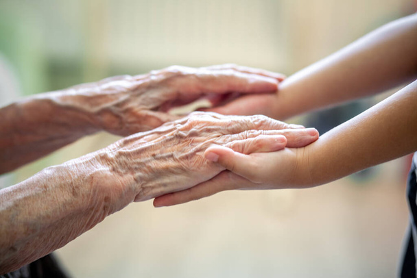 Ręce dziecka w rękach babci, stara brązowawa skóra w starszej kobiecie, matczyna miłość i opieka. - Zdjęcie, obraz