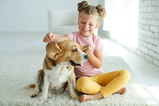 Kind met een hond. Een klein meisje speelt thuis met een hond. Kind en dier. - Foto, afbeelding