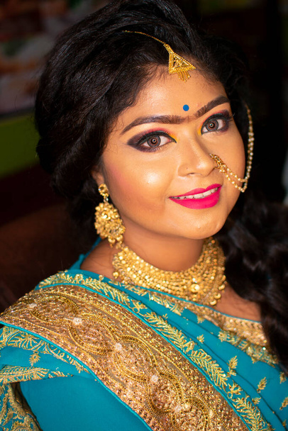 Μια έφηβη Ινδή ευτυχισμένη με ινδική εθνική ενδυμασία και στολίδια σε ένα πάρτι δεξίωσης γάμου. - Φωτογραφία, εικόνα