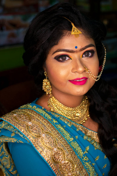 ein indisches Teenagermädchen glücklich mit indischen ethnischen Kleidungsstücken und Ornamenten bei einem Hochzeitsempfang - Foto, Bild