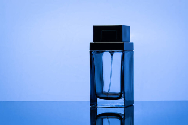 Schwarze Parfümflasche auf blauem Hintergrund. Attrappe einer schwarzen Parfümflasche - Foto, Bild