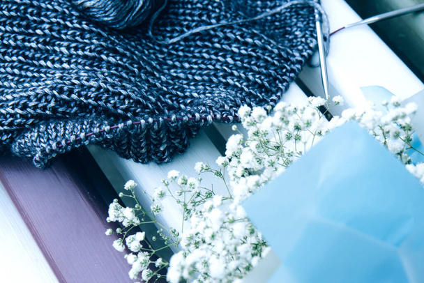 Рукоділля і букет з білих квітів на дерев'яній лавці. Текстура красива в'язана синя тканина з металевими волокнами як фон. Копіювати простір. Концепція жіночого хобі
. - Фото, зображення