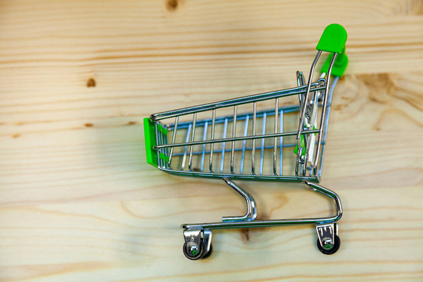 Shopping cart on a wooden background. Online shopping. - Фото, изображение