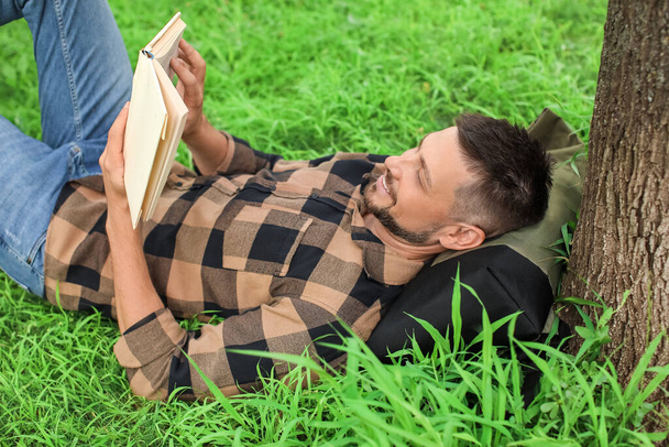 Hezký muž čtení knihy při relaxaci v parku - Fotografie, Obrázek