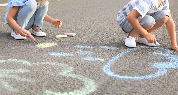 Küçük çocuklar asfalta tebeşirle resim çiziyor. - Fotoğraf, Görsel