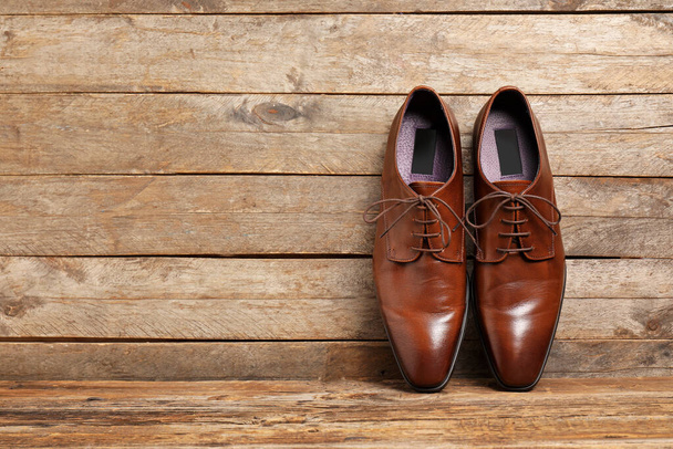 Pair of leather male shoes on wooden background - Фото, изображение