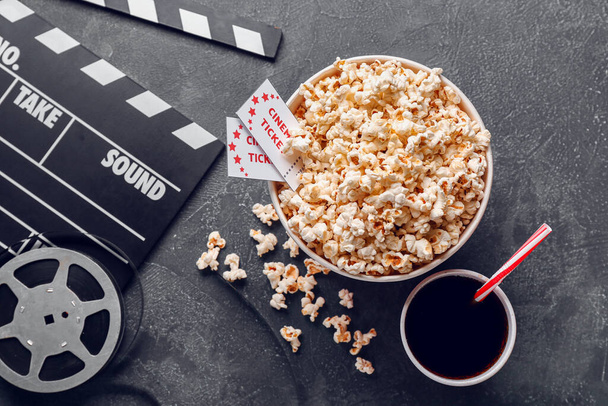 Popcorn, cola, ταινία clapper και εισιτήρια κινηματογράφου σε σκούρο φόντο - Φωτογραφία, εικόνα