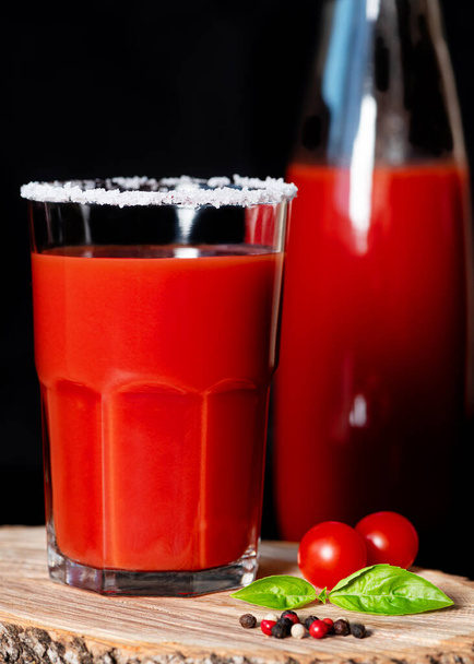 Tomatensap in glas met zilte rand op houten ondergrond. Een close-up. Rustig aan. Verticale oriëntatie - Foto, afbeelding