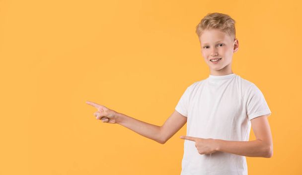Χαμογελαστή αγόρι δείχνοντας το δάχτυλο στην άκρη στο χώρο αντίγραφο - Φωτογραφία, εικόνα