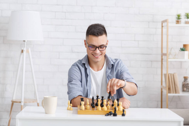 Αυτοαπομόνωση, έννοια της online εκπαίδευσης. Χαρούμενος τύπος παίζει στο σκάκι online με εικονικό συνεργάτη - Φωτογραφία, εικόνα
