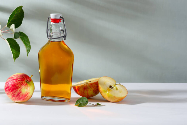 新鮮な熟したリンゴとアップルサイダー酢。ガラス瓶にアップルサイダーと新鮮なリンゴ。光の背景. - 写真・画像