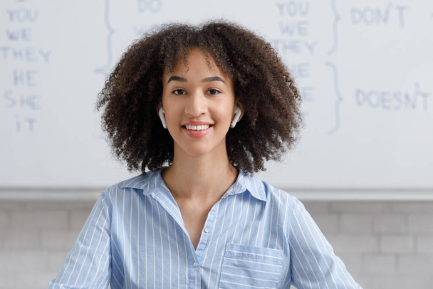 Частные уроки онлайн. Улыбающаяся африканская американка в беспроводных наушниках - Фото, изображение
