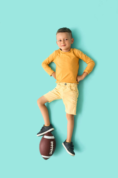 Kleiner Junge mit Rugby-Ball auf farbigem Hintergrund, Draufsicht - Foto, Bild
