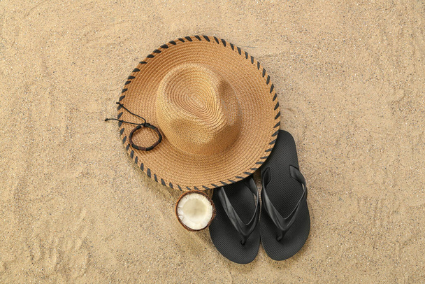 Männerhut mit Flip-Flops und Kokosnuss auf Sand - Foto, Bild