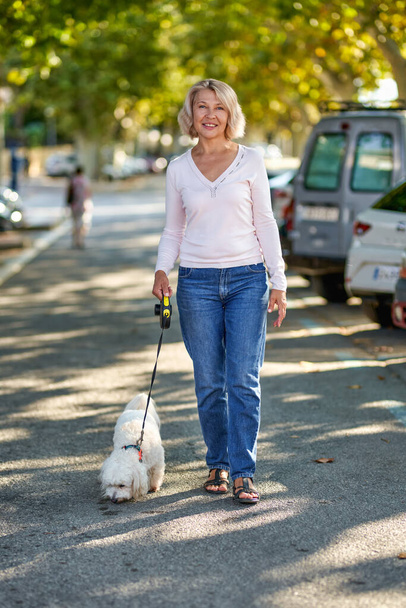 Femme mûre marchant avec un chien à l'extérieur. - Photo, image