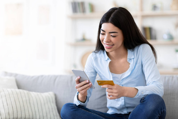 Compras en línea. Mujer asiática feliz usando la aplicación en Smartphone y tarjeta de crédito - Foto, imagen
