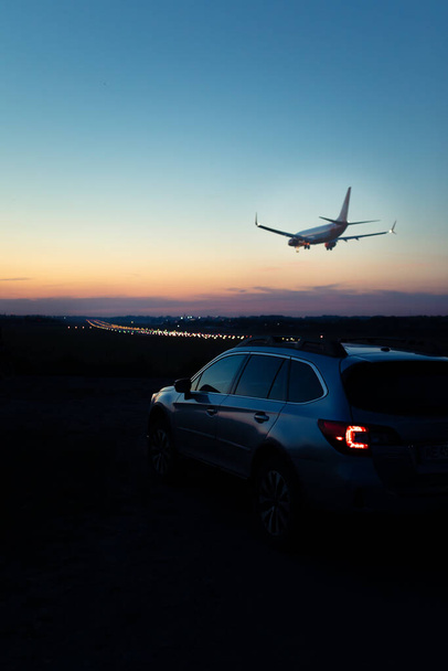 widok na samochód z tylnymi światłami samolotu lądującego na tle. skopiować przestrzeń. zachód słońca - Zdjęcie, obraz