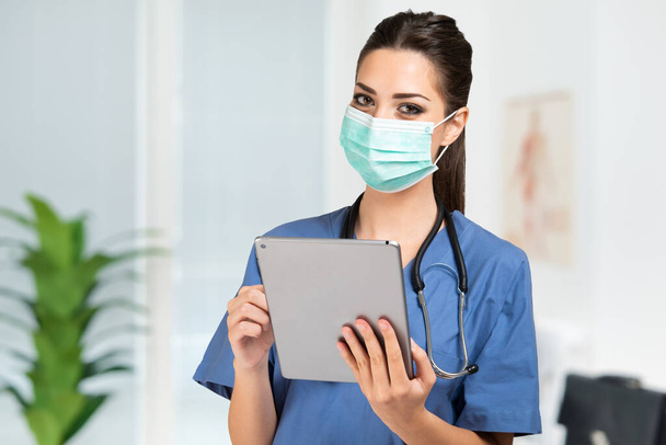 Masked young nurse doctor using a tablet - Foto, afbeelding