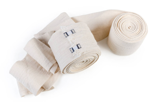 Dokuma elastik bandaj rulo içine sarılmış ve klipslerle sarılmış aynı kısmen açılmamış bandaj beyaz arka planda, üst manzara - Fotoğraf, Görsel