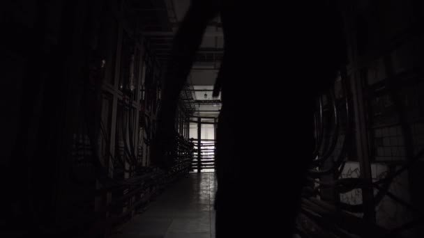 Un homme avec une lanterne marche dans un tunnel souterrain avec de nombreux câbles. - Séquence, vidéo