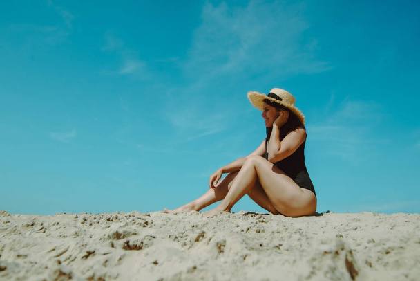 mujer en la playa de arena en traje de baño negro cielo azul sobre fondo. vacaciones de verano - Foto, imagen