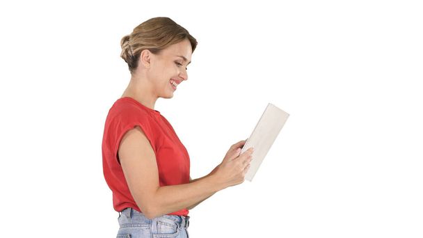 Woman in casual clothing using digital tablet walking on white background. - Photo, Image