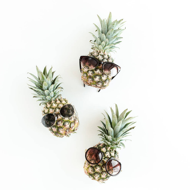 Hipster pineapples in glasses on white background. Flat lay, top view - Foto, Imagen