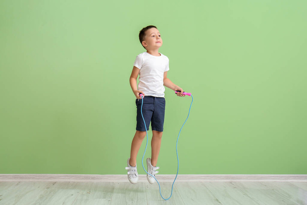 Cute little boy jumping rope near color wall - Foto, afbeelding