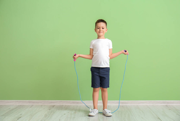 Lindo niño saltando cuerda cerca de la pared de color - Foto, imagen