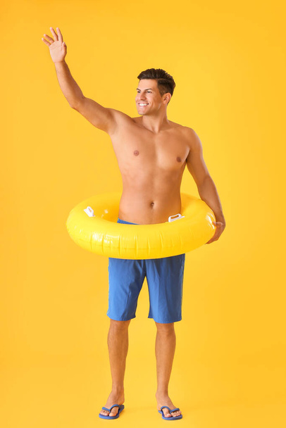 Happy young man with inflatable ring on color background - Фото, изображение