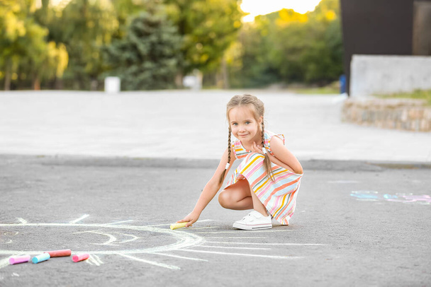 Küçük kız asfalta tebeşir çiziyor. - Fotoğraf, Görsel